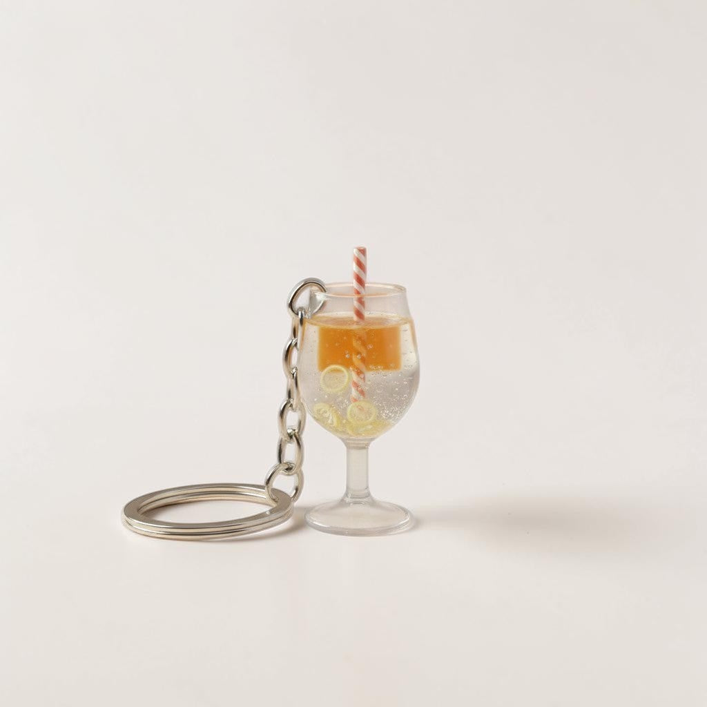 Il mio negozio Aperitivo spritz keychain, a miniature orange drink with lemon slices and a straw in a clear glass.